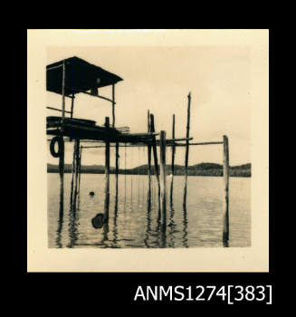 A wooden pearl structure, composed from wooden poles over water with a sheltered area on top, on Packe Island