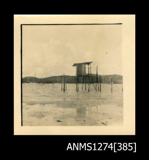 A wooden pearl structure, consisting of a shade structure on top of wooden platforms over water, on Packe Island