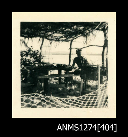 A man sitting at a bench, under a shade cover on Packe Island