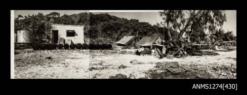 A beach, with sheds, tents, containers, and other pieces of equipment, on Packe Island