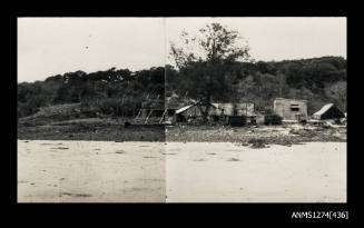 Photograph of sheds, tents and equipment on a beach, on Packe Island