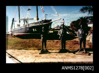 35mm colour transparency of a boat, with three statues placed in front of it