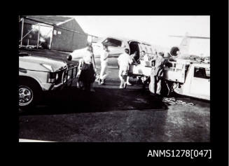 People standing next to cars, about to board a small plane