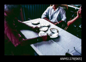 35mm colour transparency of six pearls shells on a table, with people sitting around the table