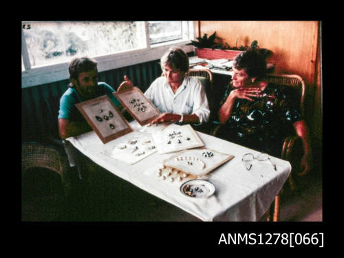 35mm colour transparency of three people sitting at a table, with pearls, etc