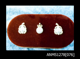 35mm colour transparency of three pearl pendants, displayed on a red board