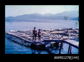 35mm colour transparency of two young boys standing on a wooden pearl raft