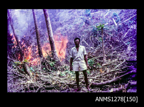 35mm colour transparency of a Papua New Guinean man standing in front of a fire in the bush