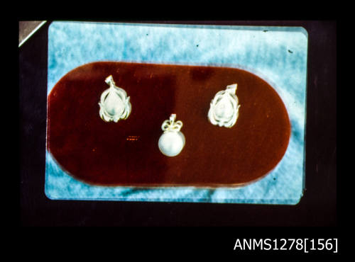 35mm colour transparency of three pearl pendants on red padding