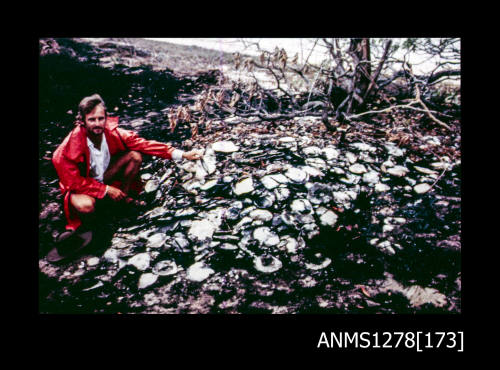 35mm colour transparency of a man crouching next to a pile of pearl shells