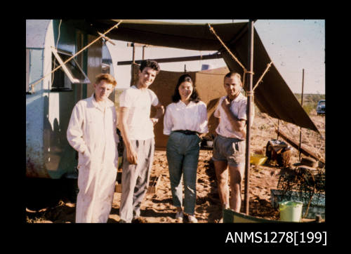 35mm colour transparency of Yurie (or Yulie) George and three men, standing on a beach next to a caravan