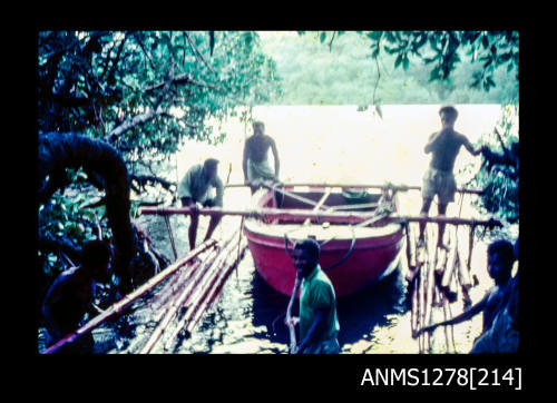 35mm colour transparency of a red boat, with wood beams on both sides, and people standing around the boat