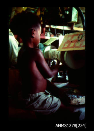 35mm colour transparency of a young Papua New Guinean boy working on a pearl grinding [?] machine