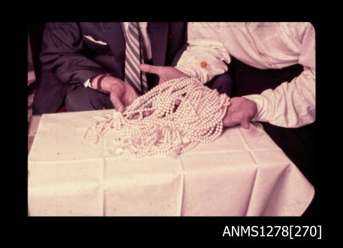 35mm colour transparency of two people holding numerous strings of pearls