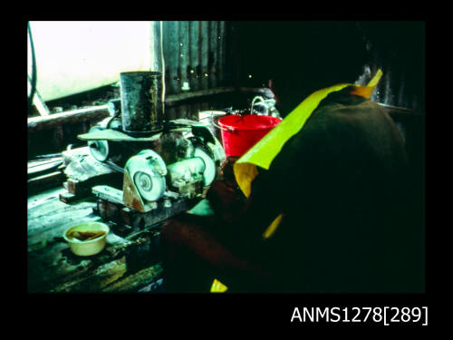 35mm colour transparency of a person working in a shed at a machine, possibly a grinder