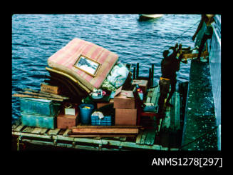 35mm colour transparency of boxes, furniture, a matress, etc being transported on a barge