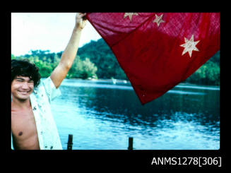 35mm colour transparency of Nick [?] George, holding a red flag with stars on it