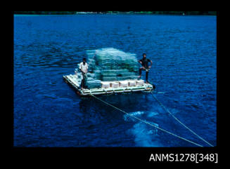 35mm colour transparency of a raft, carrying two men and a large pile of pearl cages, attached to two ropes