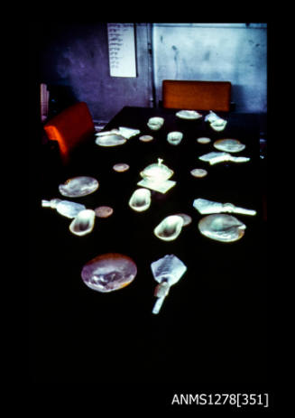 35mm colour transparency of a table, laid out with pearl shell plates, bowls, coasters and serviette rings