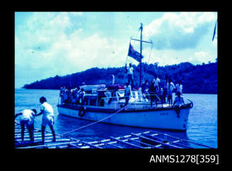 35mm colour transparency of the boat ERLO, with numerous Papua New Guinean people on board, with a rope thrown to two men on a raft