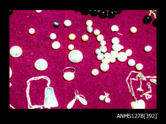 35mm colour transparency of of pearls, half pearls (or mabe pearls), and pearl shell and shell jewellery on a red base