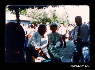Queen Elizabeth II and Prince Philip with Denis George, viewing a pearl seeding demonstration, with the Queen pointing at an object, during their visit to Papua New Guinea in 1977