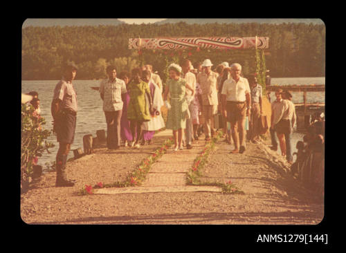 Queen Elizabeth II, Prince Philip, Denis George, and others, walking on a carpet after stepping off a boat, during their visit to Papua New Guinea in 1977