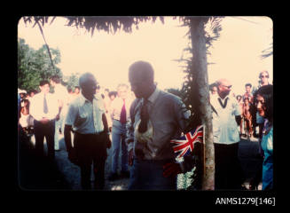 Prince Philip, wearing a pearl shell necklace, with Denis George standing behind him, during his and Queen Elizabeth II's visit to Papua New Guinea in 1977
