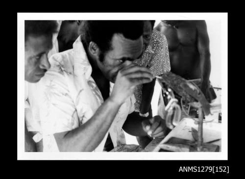 A Papua New Guinean man seeding a pearl shell, held in place with a clamp