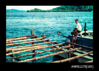 Strip with one negative of two people sitting on a boat, next to a pearl production raft