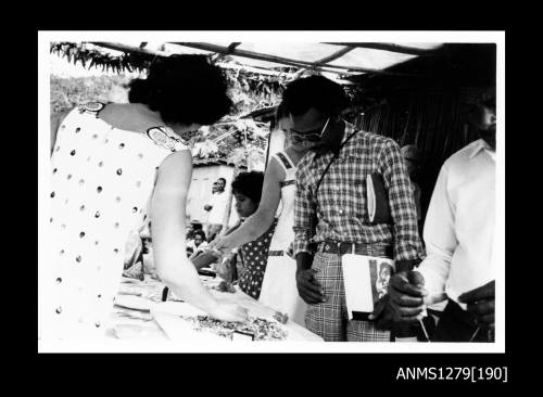 Two men, two women and a child looking at a display of pearls on a table