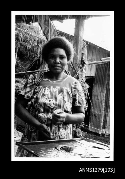 A Papua New Guinean woman, standing in front of a tray containing pearl shell pieces