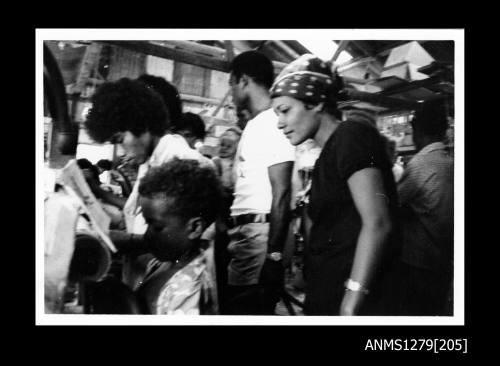 Photograph of several Papua New Guinean people, including a woman wearing a scarf around her head, and a young boy