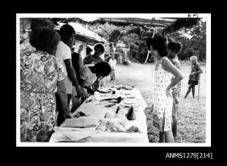 Yurie (or Yulie) George and several Papua New Guinean men and women viewing a pearling display laid out on a table