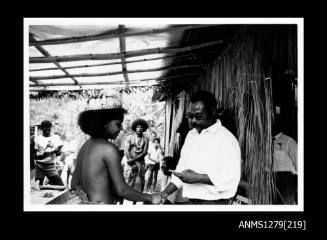 A Papua New Guinean man shaking hands with a Papua New Guinean girl in traditional dress