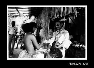 A man wearing glasses, shaking hands with a Papua New Guinean girl in traditional dress