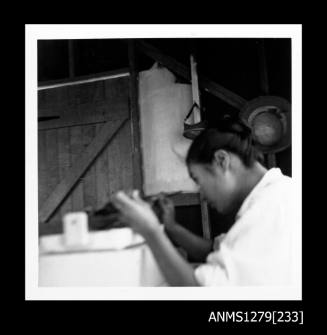 Yurie (or Yulie) George, sitting at a desk seeding a pearl shell