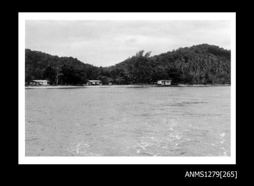 A pearl raft near the shoreline, on which sits two sheds (or houses)