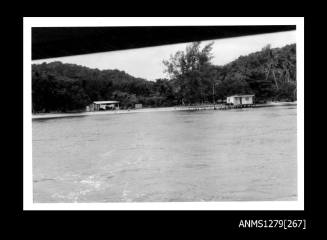 A pearl raft near the shoreline, on which sits a shed with washing hanging out the front