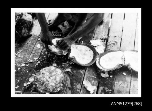 A person removing the flesh from a pearl shell