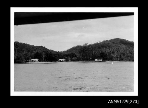 A pearl raft near the shoreline, on which are two sheds, or houses