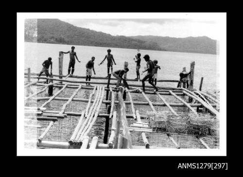 Photograph of several Papua New Guinean men constructing a pearl raft out of wood