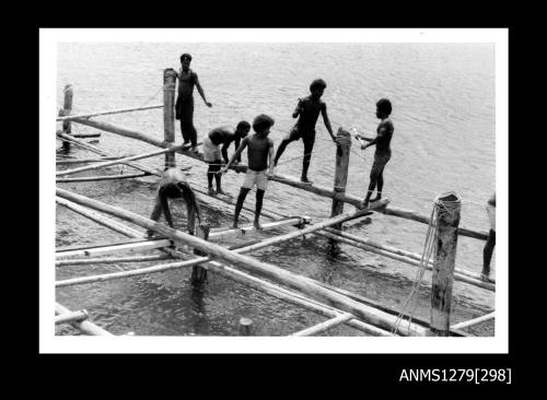 Photograph of several Papua New Guinean men constructing a pearl raft out of wood