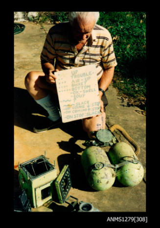 Colour photograph of two green air tanks, underwater camera and green underwater camera case, sitting on the ground