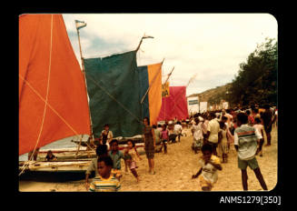 Colour photograph of boats with coloured flags lined up on the beach for the Pacific Festival on Pearl Island, with onlookers standing on the sand