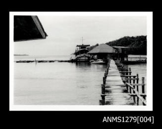 A wharf with two boats docked next to a building at the end of the wharf