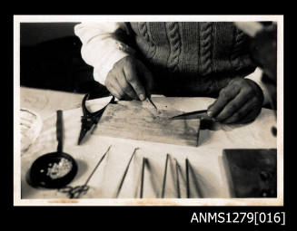 A man using pearl seeding tools on a wooden board