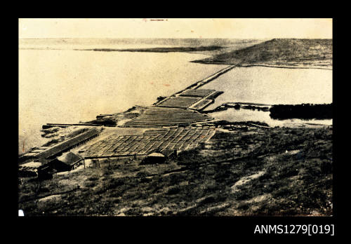 A structure, built in land and over the water, with a long bridge [?] over the water to the land on the opposite side