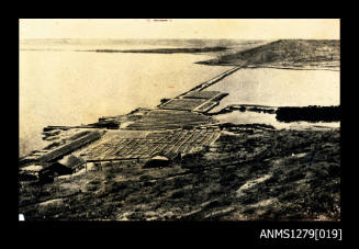 A structure, built in land and over the water, with a long bridge [?] over the water to the land on the opposite side