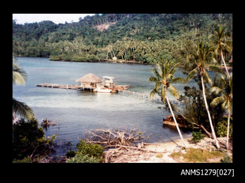 Colour photograph of a pearl raft and building, over the water, in Cairns